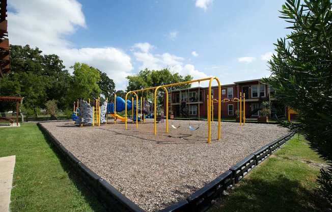 A playground with a swing set and a slide at Willow Creek Apartments, Houston