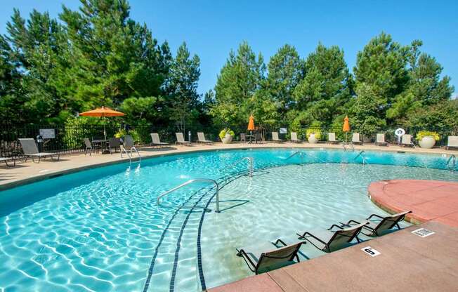 A large outdoor swimming pool with a wooden deck and lounge chairs.