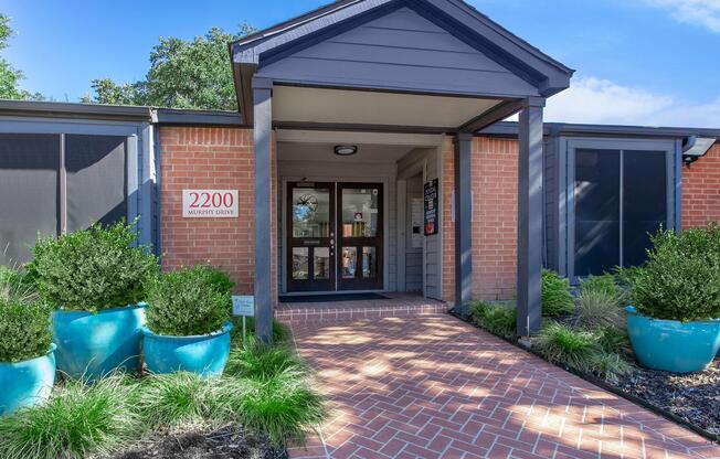 a house with trees in the front yard of a brick building