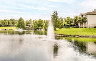 Large community lake with a water feature surrounded by grass and native landscape.