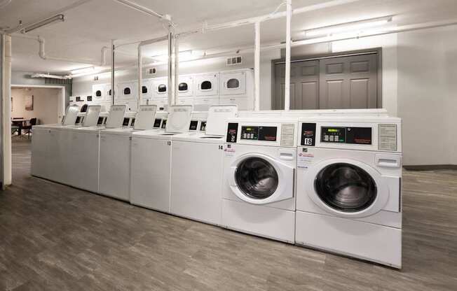 A row of industrial washing machines in a laundry facility.