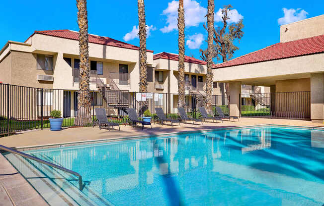 A swimming pool in front of a building with palm trees.