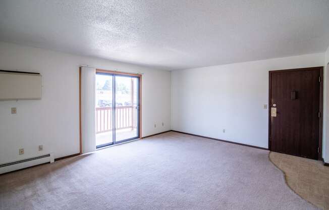 A living room with a door to a balcony. Bismarck, ND Eastbrook Apartments.