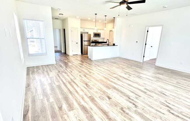 A spacious living room with a kitchen in the background.