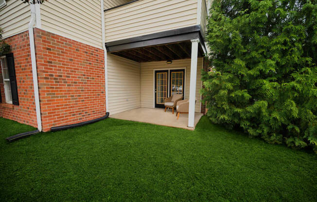 a covered porch with a lawn and a brick house