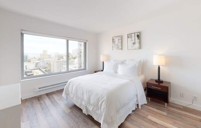 a bedroom with a large window and hardwood floors