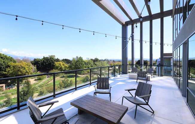 A patio with chairs and a table overlooking a green landscape.