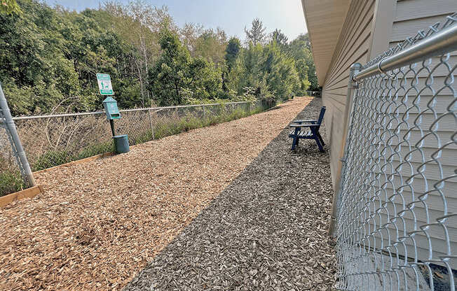 a bench on a gravel path next to a fence