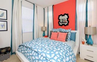 a bedroom with a bed and a red wall and white curtains at The Vines at Riverpark, LLC, Oxnard, CA 93036