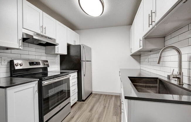 a kitchen with white cabinets and black appliances