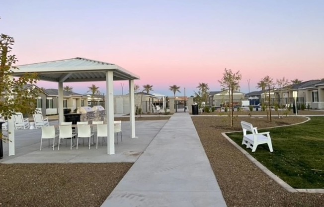 a pathway leading to a picnic area with chairs and tables