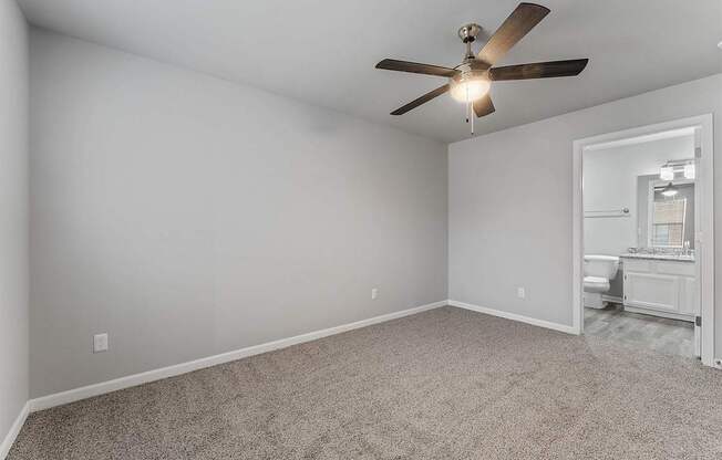 A room with a ceiling fan and carpeted floor.