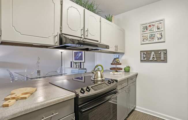 an apartment kitchen with stainless steel appliances and white cabinets