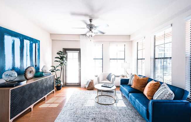 a living room with a blue couch and a ceiling fan