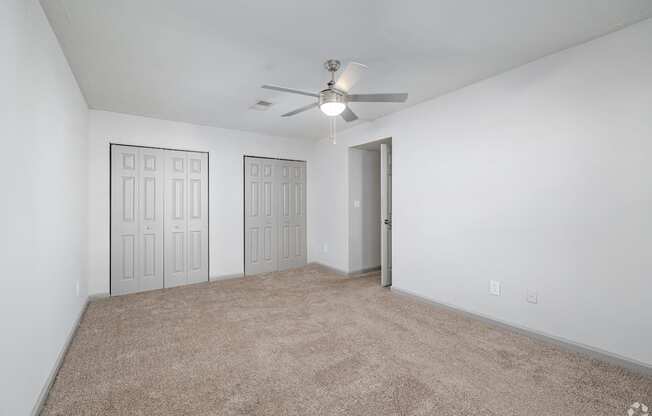 A room with a ceiling fan and carpeted floor.