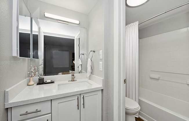 Model Bathroom with White Cabinets, Wood-Style Flooring and Shower/Tub at Crystal Creek Apartments located in Phoenix, AZ.