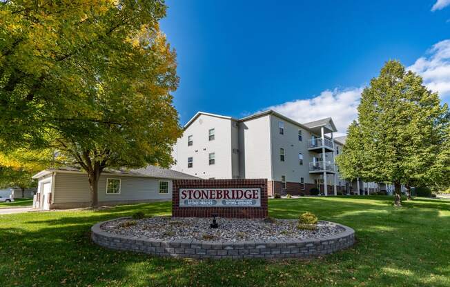 An exterior of an apartment with a sign and underground garage out front.  Fargo, ND Stonebridge Apartments.