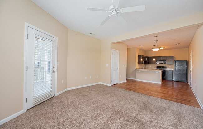 an empty living room with a ceiling fan and a kitchen