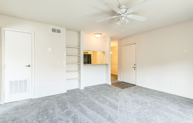 A room with a ceiling fan and carpeted floor.