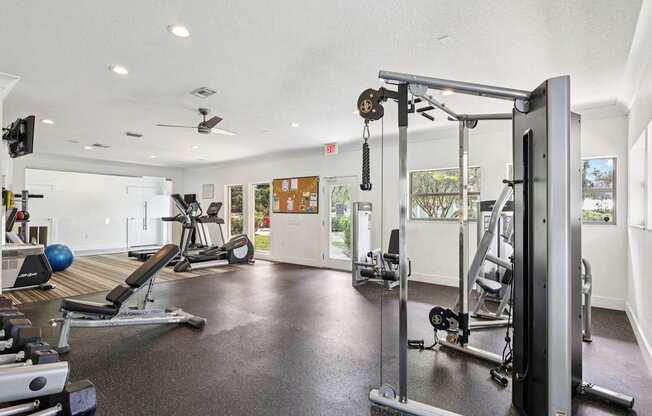 A gym with a variety of equipment including a weight bench, a treadmill, and a squat rack.