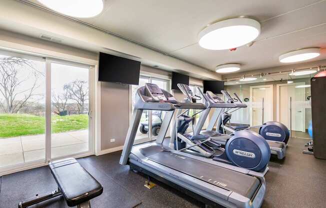 A gym with treadmills and a television.