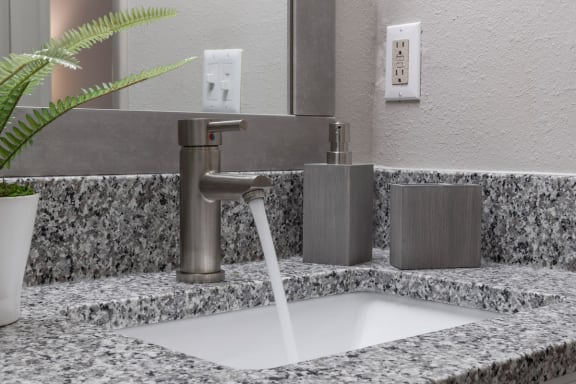 granite bathroom vanity with modern fixture with flowing water and decor at Preserve at Cedar River Apartments, Jacksonville, FL