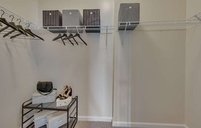 A room with a shelf, hangers, and shoes.