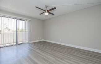 an empty bedroom with a ceiling fan and blinds