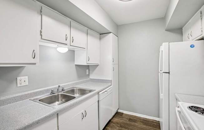 A kitchen with white cabinets and a white refrigerator.