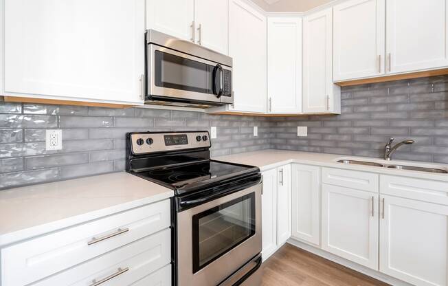 a kitchen with white cabinets and stainless steel appliances