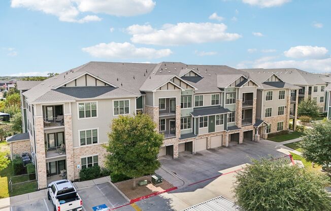 A large apartment complex with a parking lot in front.
