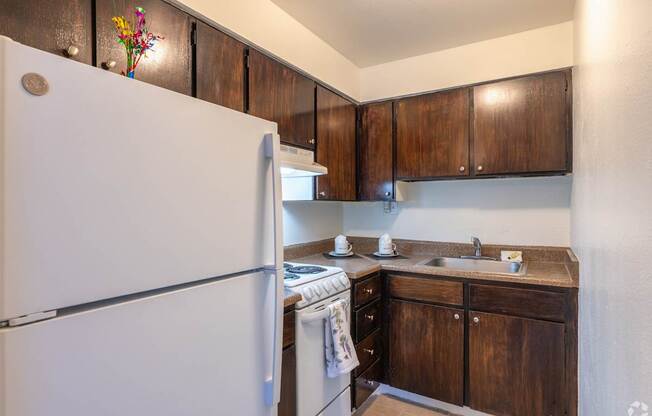 Kitchen with white refrigerator and brown cabinets.
