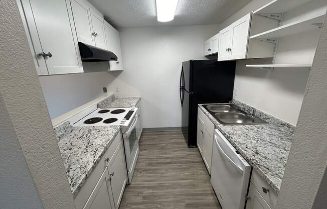 a kitchen with white cabinets and granite counter tops and a black refrigerator at Kings Court, Anchorage, 99501 ? 