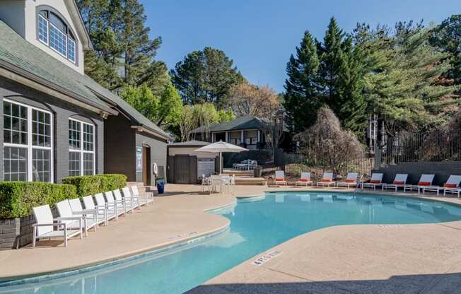 a swimming pool with chairs around it in front of a house