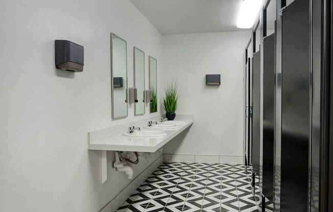 a bathroom with a black and white tiled floor and stalls at Presidio Palms Apartments, Arizona, 85701