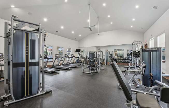 A gym with a variety of equipment including treadmills, weights, and exercise machines at Creekside on Parmer Lane Apartments in Austin, TX