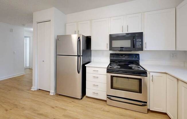 A kitchen with a refrigerator, oven, and microwave.