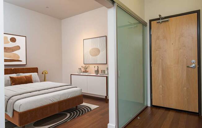 A bedroom with a bed, nightstand, and artwork.