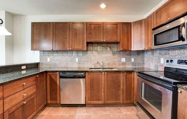 A kitchen with brown cabinets and black appliances.