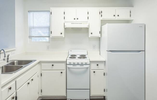 a kitchen with white cabinets and a white stove and refrigerator