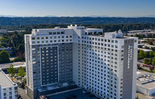 A large white hotel building with a parking lot in front.