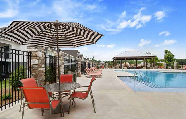 A patio with a table and chairs is set up next to a pool.