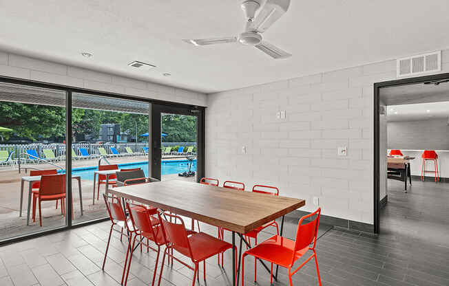 a dining room table with red chairs and a ceiling fan