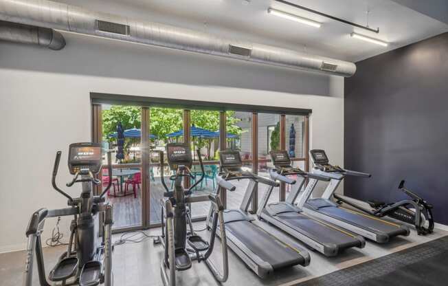 a gym with cardio machines and a patio with a pool