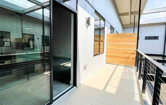 A glass door is open to a hallway with a wooden wall.