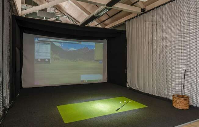 a golf simulator in a room with a screen and a golf ball