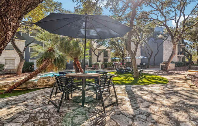 A patio with a table and chairs under an umbrella.