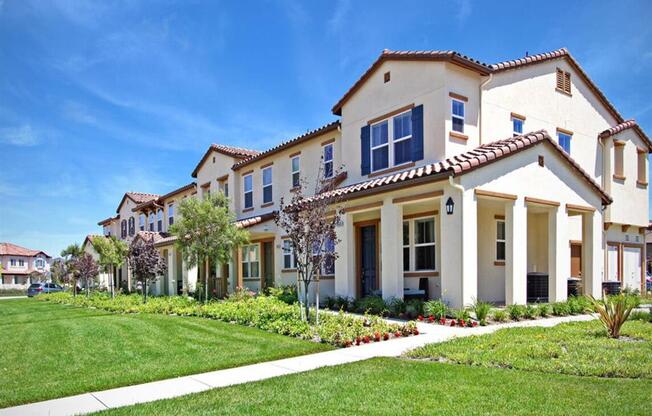 a row of houses on the side of a green lawn at The Vines at Riverpark, LLC, Oxnard California