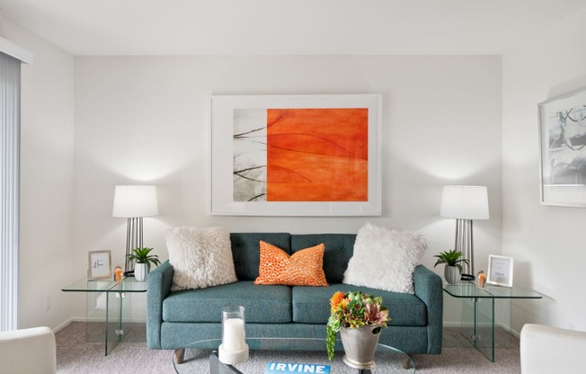 a living room with a blue couch and a orange painting on the wall