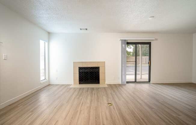 an empty living room with a fireplace and sliding glass doors